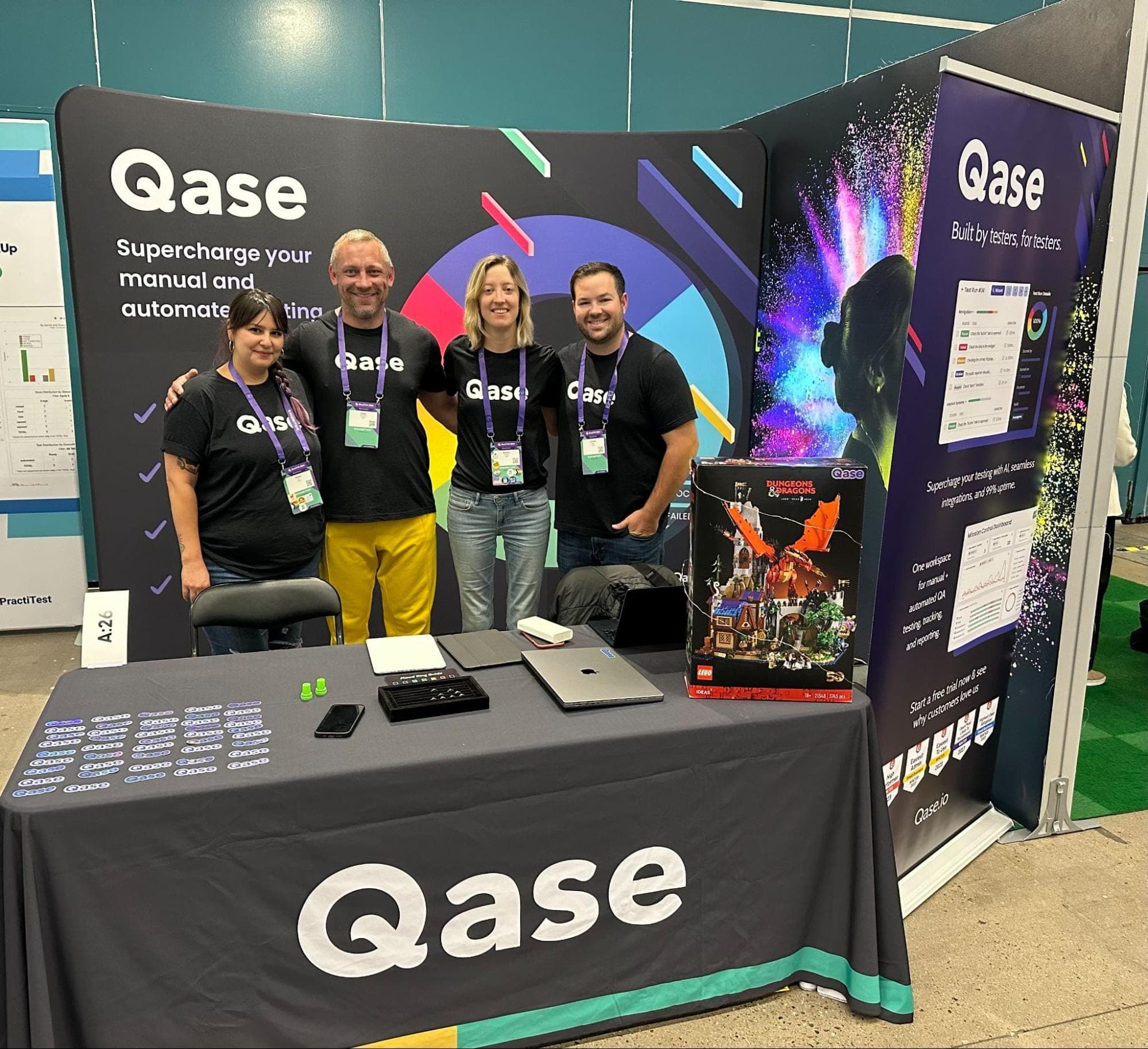 Rease Rios, Vitaly Sharovatov, Breezy Baldwin, and Connor HejMej wearing black Qase t-shirts and EuroSTAR badges at Qase table.